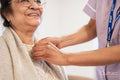 Nurse helping senior lady to get dressed at nursing home