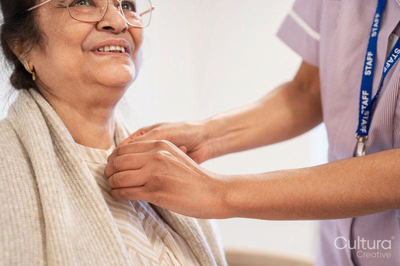 Nurse helping senior lady to get dressed at nursing home