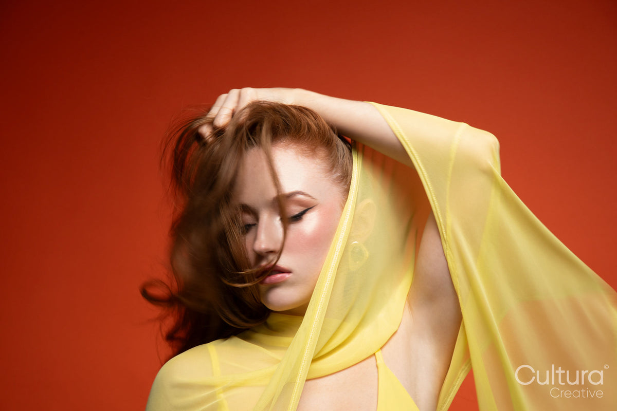 Studio portrait of a woman in a yellow dress with windswept hair