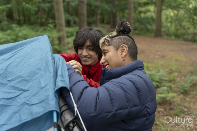 Mother and son setting up tent in forest