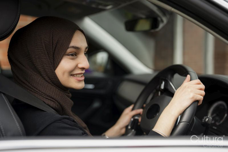 Young woman wearing hijab driving car