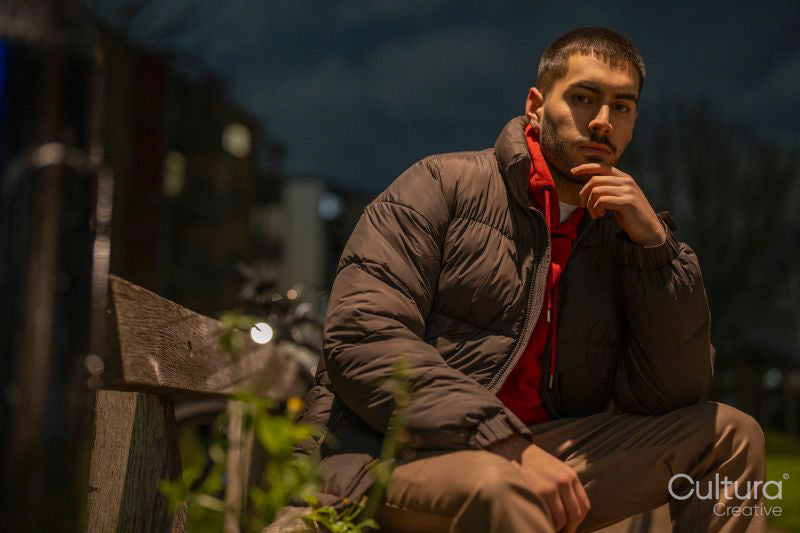 Portrait of young man sitting on bench at night