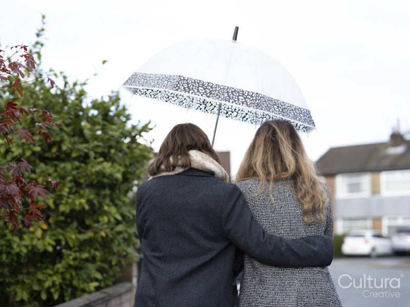 Back view of two women wearing coats under umbrella in rain