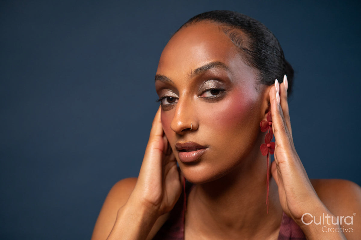 Woman in a burgundy dress with red earrings on a blue background