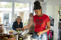 Two women and teenage girl preparing meal in kitchen