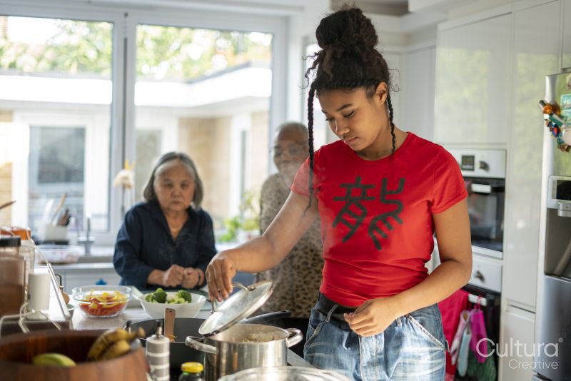 Two women and teenage girl preparing meal in kitchen