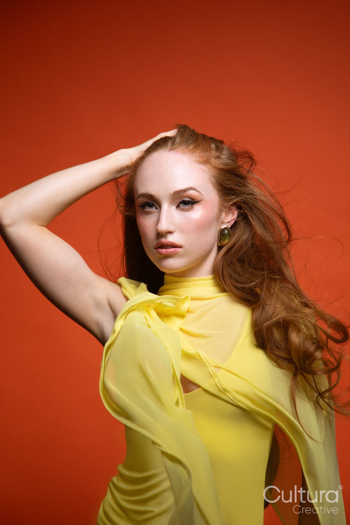 Studio portrait of a woman in a yellow dress with windswept hair