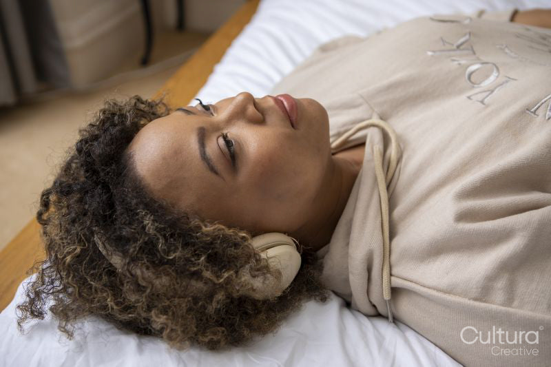 Woman with headphones listening music on bed