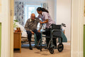 Nurse helping senior man to sit on wheelchair at nursing home