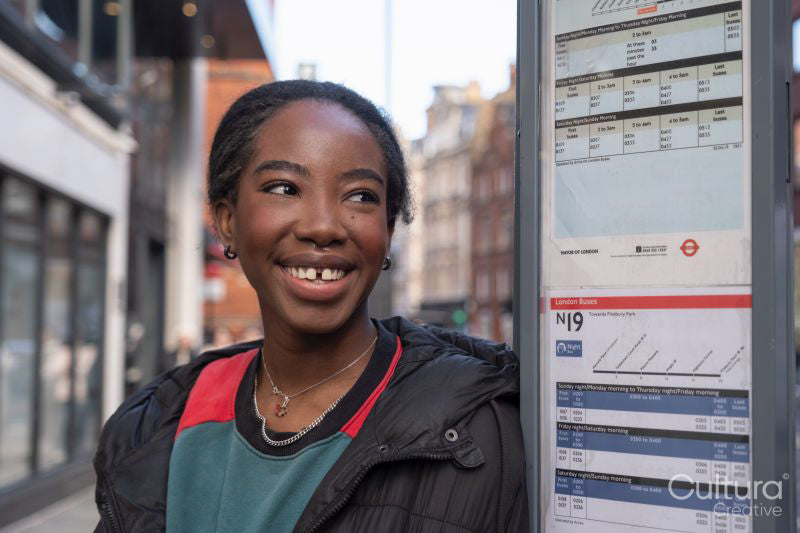 Portrait of happy young woman waiting on bus stop