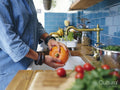 Woman washing pumpkin in kitchen sink