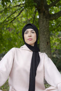 Portrait of woman in hijab and pink tracksuit sitting in park