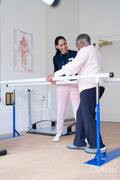 Smiling female therapist assisting senior woman walking on bars