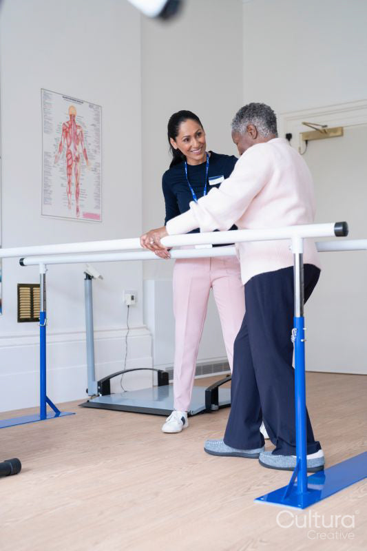 Smiling female therapist assisting senior woman walking on bars
