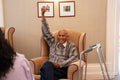 Smiling senior man raising arm during bingo game in nursing home