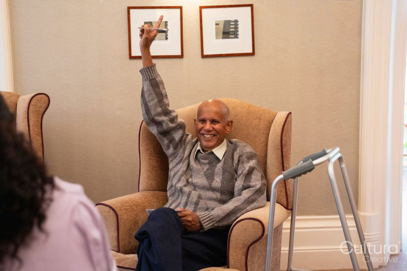 Smiling senior man raising arm during bingo game in nursing home