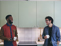 Two smiling men talking in kitchen
