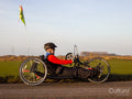 Disabled man riding handcycle on country road
