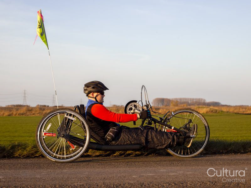 Disabled man riding handcycle on country road