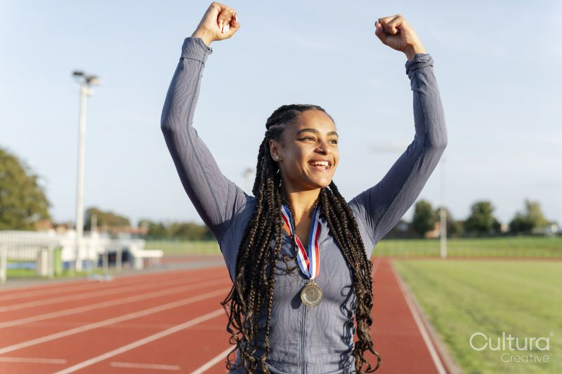 Portrait of female athlete celebrating with medal