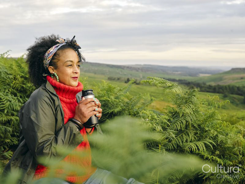 Woman holding insulated drink container and looking at landscape