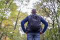 Back view of man with backpack in forest at autumn