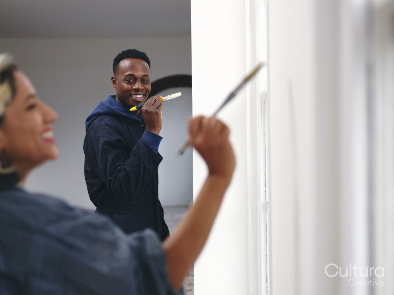 Smiling couple painting house walls