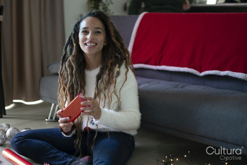 Woman sitting on floor in living room preparing Christmas presets