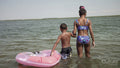 Rear view of brother and sister wading in sea with inflatable ring