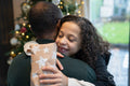 Smiling girl holding Christmas gift and embracing father