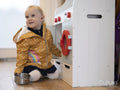 Girl wearing raincoat playing with toy kitchen at home