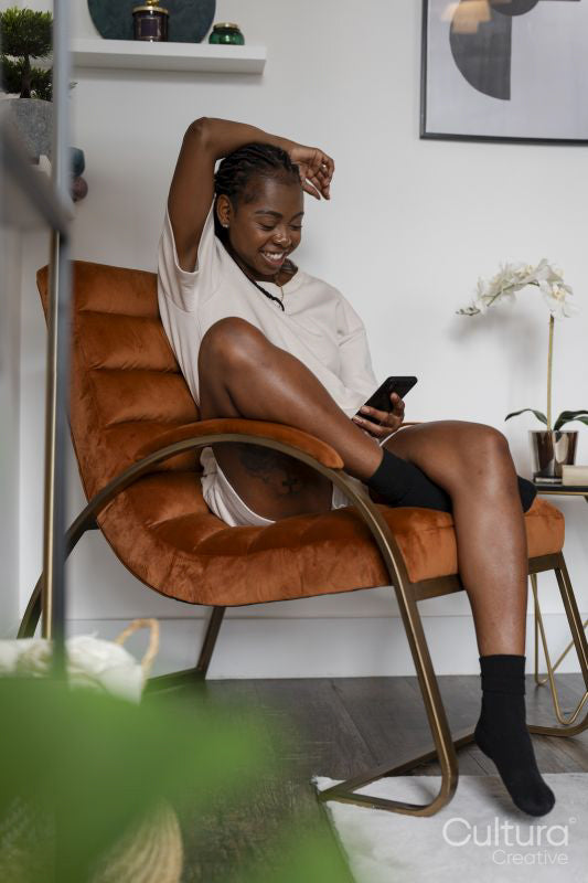 Young woman using smart phone while sitting in armchair at home