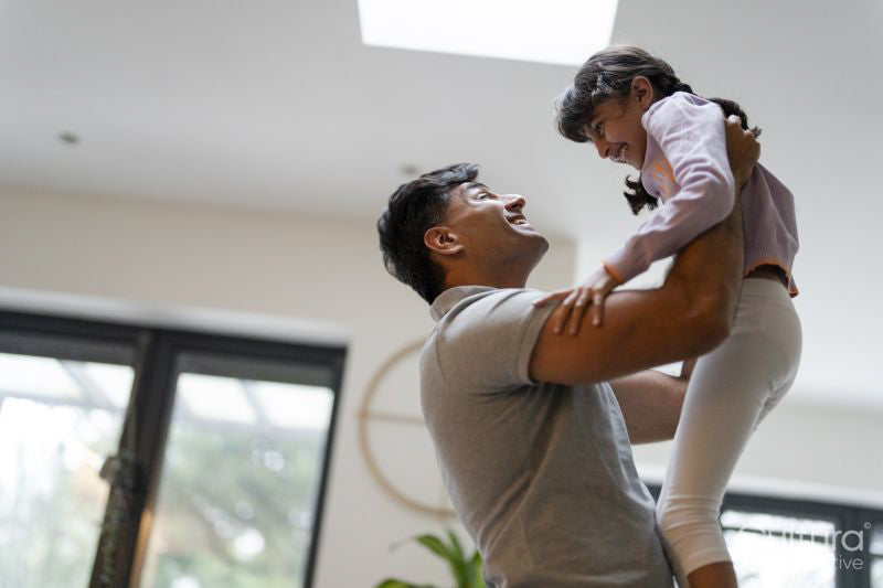 Father lifting daughter at home