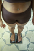 Low section of woman in lingerie standing on bathroom scale