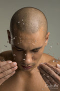 Studio shot of shirtless man splashing water on face