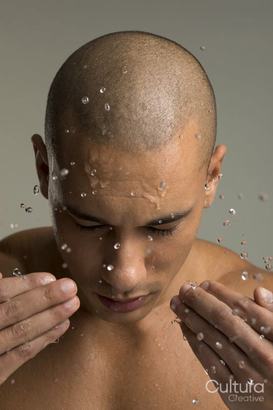 Studio shot of shirtless man splashing water on face