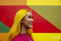 Smiling young woman with yellow hair against colorful wall