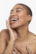 Studio portrait of woman with short hair and nose ring laughing with eyes closed