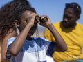Boy looking through binoculars on beach