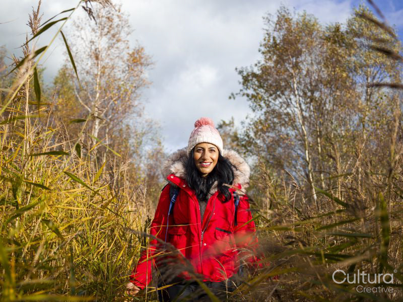 Smiling female hiker walking through tall grass
