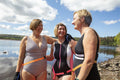 Female friends in swimsuits standing on rocky lakeshore, Yorkshire, UK