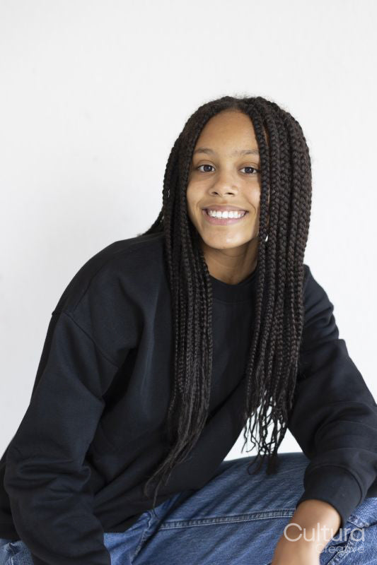 Portrait of smiling girl squatting with hand on knee on white background