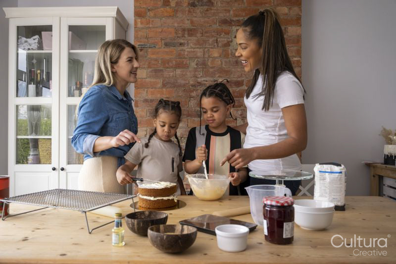 Mothers and sons making cake in kitchen