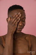Smiling young woman covering face against pink background