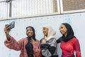 Smiling young women wearing hijabs taking selfie