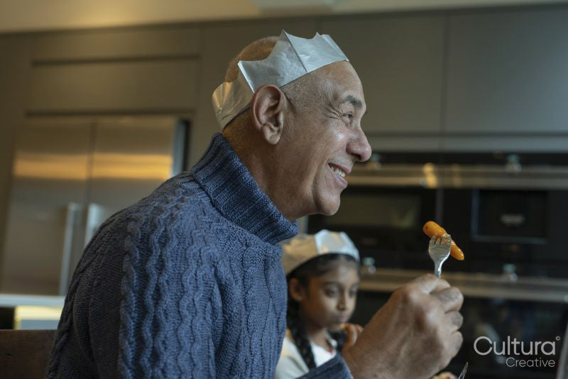 Smiling man wearing paper crown enjoying Christmas dinner