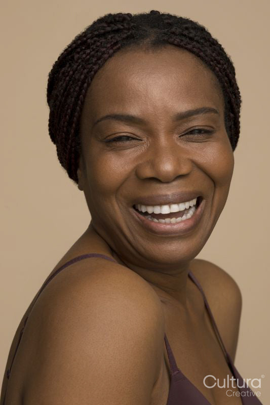 Studio portrait of mature woman with braided hair laughing