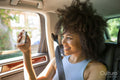 Young woman sitting in car and taking selfie