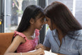 Smiling mother and daughter face to face at home