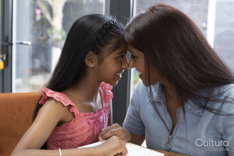 Smiling mother and daughter face to face at home
